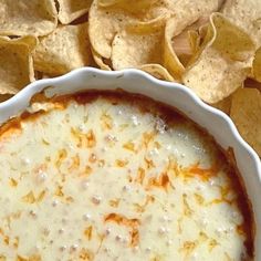 a white bowl filled with dip surrounded by tortilla chips