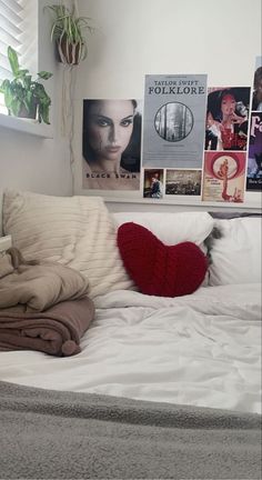 a bed with pillows and blankets on top of it next to a wall with pictures