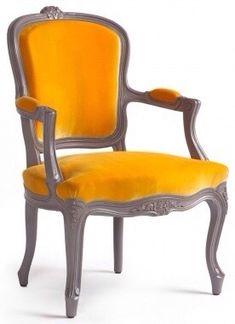 an old fashioned chair with yellow velvet upholstered on the back and armrests