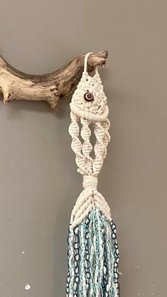 a white and blue macrame hanging on a wall next to a driftwood branch