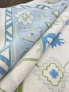 two pieces of fabric sitting on top of a wooden table next to a white and blue rug