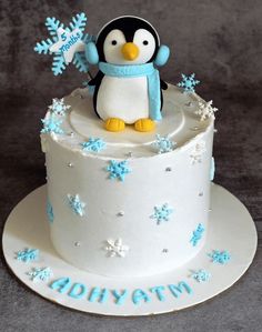 a birthday cake decorated with a penguin and snowflakes