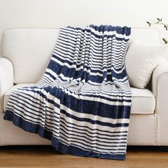 a blue and white blanket sitting on top of a couch next to a white sofa