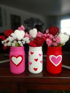 three painted mason jars with hearts and flowers in them