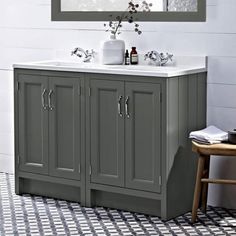 a bathroom vanity with two sinks and a mirror above it, in front of a tiled floor