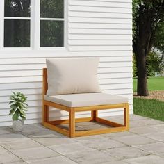 a wooden chair sitting on top of a patio next to a white house with a potted plant