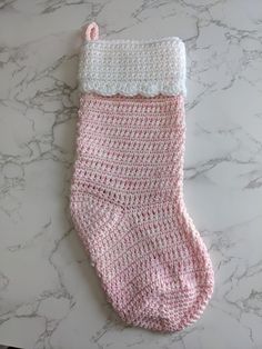 a pink and white crocheted sock laying on top of a marble counter