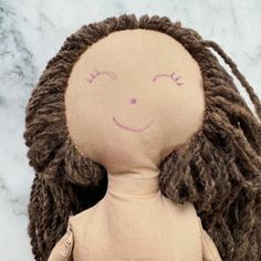 a stuffed doll with dreadlocks on it's head is posed in front of a marble background