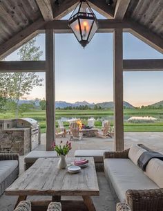 a covered patio with table, couches and grill in the background at dusk or dawn