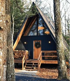 a small cabin in the woods with stairs leading up to it's front door