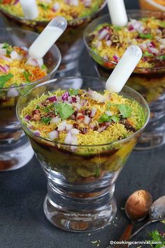 several bowls filled with food and garnished with white plastic utensils on a table