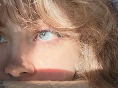 a close up of a child's face with long hair and blue eyes looking at the camera