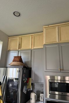 a kitchen with stainless steel appliances and wooden cabinetry on the wall, along with a light fixture