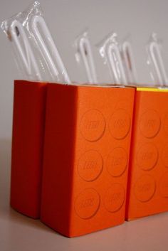 three orange legos are stacked on top of each other with toothbrushes sticking out of them