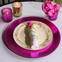 a plate with a napkin on it and pink flowers in vases next to it