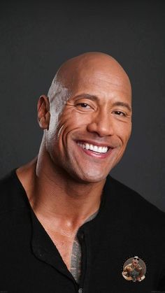 a bald man smiling and wearing a black shirt