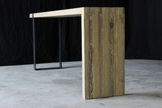 a wooden table sitting on top of a cement floor next to a black wall in front of it