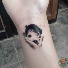 a woman's hand with a small tattoo on it that has an image of a dog