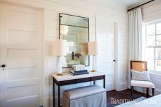 a bedroom with white walls and wood flooring, along with a desk that has a mirror on it