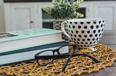 a pair of glasses sitting on top of a table next to a book and cup