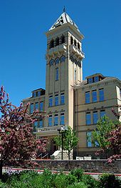 a tall building with a clock on the top of it's tower and trees in front of it