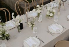 the table is set with white flowers and place settings for guests to sit down at