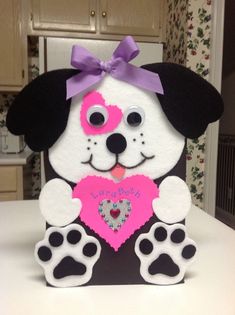 a paper cut out of a dog holding a heart in its paws and wearing a purple bow