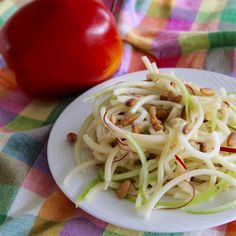 a white plate topped with food next to an apple on top of a table cloth