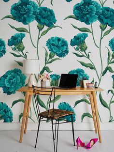 a desk with a laptop on it next to a flower wallpaper