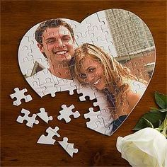 a heart shaped puzzle with two people on it and a white rose in the foreground