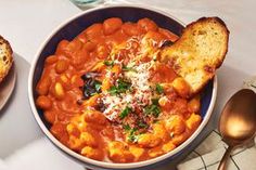 two bowls filled with beans and bread on top of a table