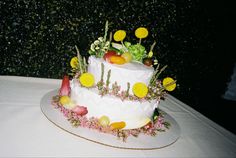 a white cake with flowers and fruit on it