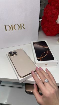 a woman's hand holding onto the back of an iphone in front of a box