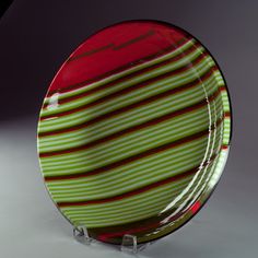 a green and red striped glass plate on a clear stand