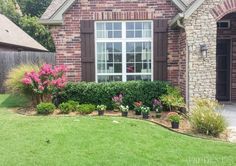 a brick house with flowers in the front yard