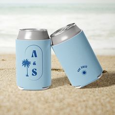 two can coolers sitting in the sand at the beach, one with a palm tree on it