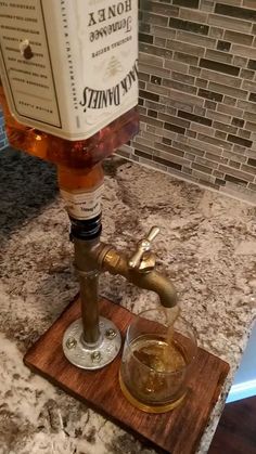 a bottle of whiskey sitting on top of a wooden coaster next to a faucet