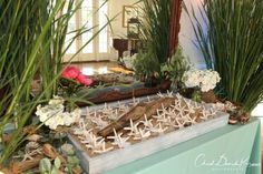 a table topped with lots of fake plants and wooden sticks in front of a mirror