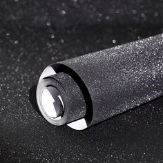 a black and white photo of a lighter on a table with some glitter around it