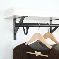 two sweaters are hanging on a rack with clothes hangers in front of them