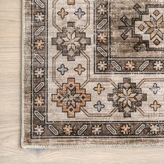 a beige rug with an intricate design on the top and bottom, sitting on a wooden floor