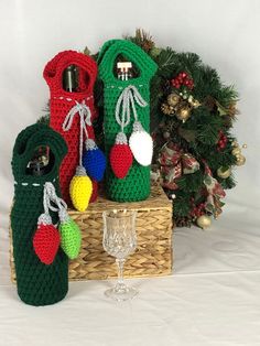 three crocheted wine bottle covers in front of a christmas tree with a goblet