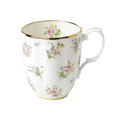 a white cup with flowers on it and gold trimmings around the rim is shown