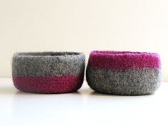 two gray and pink felt bowls sitting next to each other on top of a table