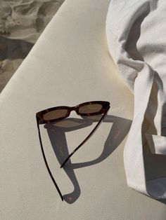 a pair of sunglasses sitting on top of a white surface next to a towel and cloth