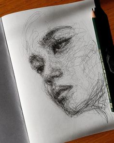 a pencil drawing of a woman's face on top of a notebook with a pen