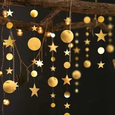 some gold stars hanging from a branch with lights on the branches and in the background