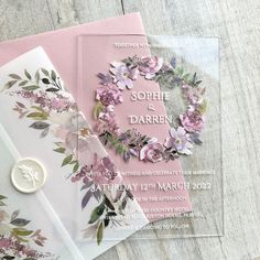 two wedding cards with flowers on them and a wax seal in front of the card