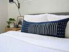 a bed with white sheets and blue pillows