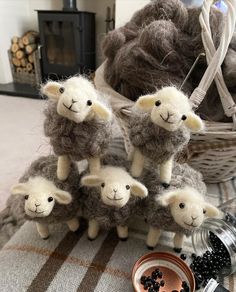 four stuffed sheep sitting on top of a table next to a bowl of blackberries